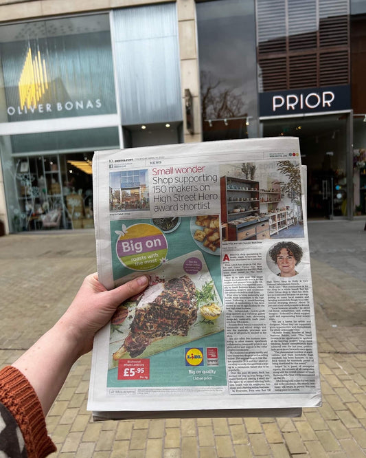 Picture of a hand holding a Bristol Newspaper in front of Prior Shop and Oliver Bonas Bristol